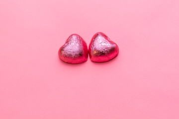Concept of 14 february or Valentine Day. Chocolate bonbons hearts in a pink wrapper. Pink background. Copy space