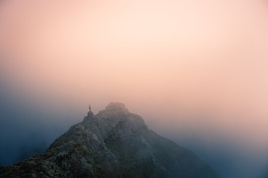 Distant view of explorer standing on mountain ridge on foggy morning during vacation in Tenerife