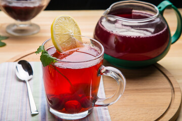 Berry tea in a cup and a teapot on a table on a round wooden stand top view.