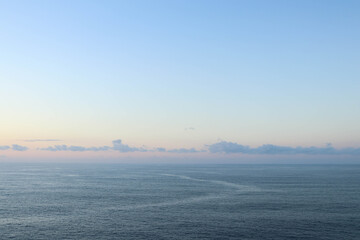 Fototapeta premium Calm sea with sunset sky and sun through the clouds over
