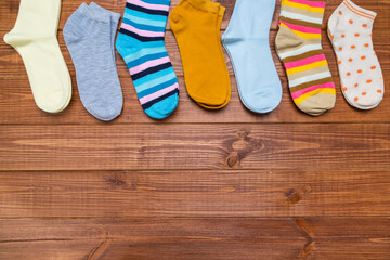 multicolored new socks in different sizes stacked on a wooden background. clothes for women