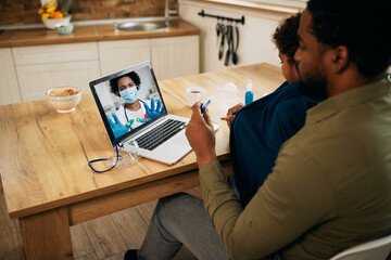 Female doctor talking to father and son via video call during coronavirus pandemic.