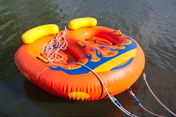 Double inflatable raft of orange color on the water surface.