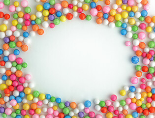 Colorful bright candy on a white background spread out in the form of a wreath frame. Top view of small balls with copy space for text