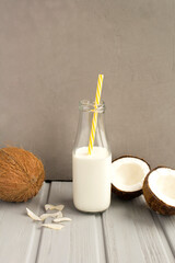 Coconut  milk in the glass bottle and coconuts on the grey  background