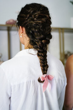 Back view of unrecognizable female with tender braid with ribbon standing in bright hairstyle salon