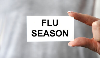 The girl holds a card with the text OF FLU SEASON in front of her.