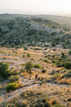 From above view of male and female in sportswear running on narrow path on hill while practicing trail running together