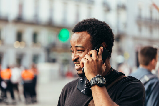 Smiling Black Man Talking On Cellphone With Serious Expression In The Street