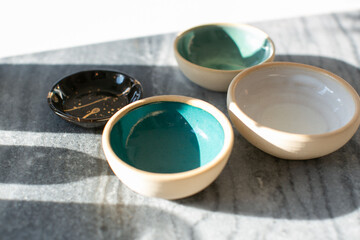 Small teal and white ceramic bowls on grey and white coffee table in the sunlight
