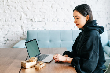 young asian girl buying christmas presents in online shopping, sales and discounts promotions during the Christmas holidays, online shopping at home and lockdown coronavirus.Xmas