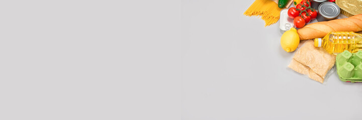 Banner with flat lay composition - food donations on grey background with copyspace - pasta, fresh vegatables, canned food, baguette, cooking oil. Food donation or food bank concept