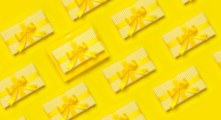 Pattern of yellow gift present box with ribbon and bow on yellow background top view copy space....