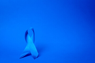 Prostate care. Awareness of men health in November with blue prostate cancer ribbon isolated on deep blue background. World cancer day and world diabetes day concept.
