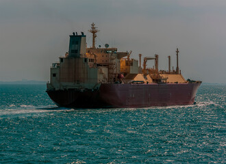 Fototapeta premium A large liquid Natural Gas tanker sailing ahead into the sunset in the Singapore Straits in Asia in summertime