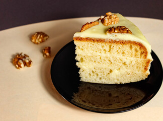 A piece of homemade cake with cream, decorated with walnuts.