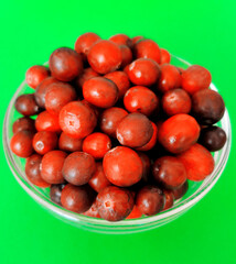 Freshly washed raw cranberries in a glass bowl on green background