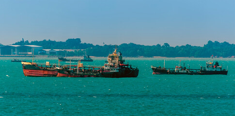 A group of small tankers moored offshore in the Singapore Straits in Asia in summertime