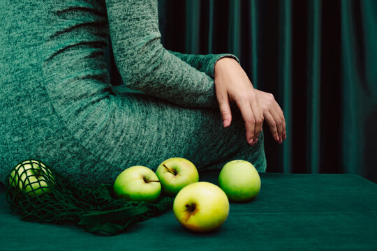 Midsection of female with green apple on table