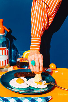 Arm of woman eating fried eggs with chorizo