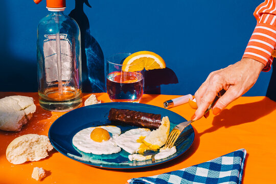 Arm of woman eating fried eggs with chorizo