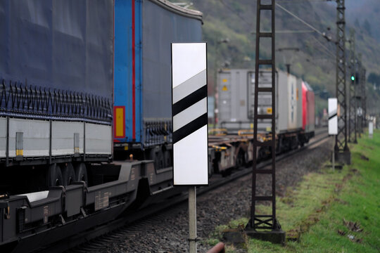 Güterzug mit Niederflurwagen zur Beförderung von Sattelaufliegern, Lastwagen und Sattelzügen auf freier Strecke mit Signal auf Grün - Stockfoto