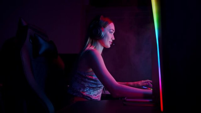 Tattooed sexy young woman playing game in neon gaming club