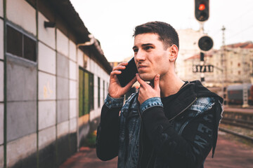 Young caucasian man talking by mobile phone at the train station.