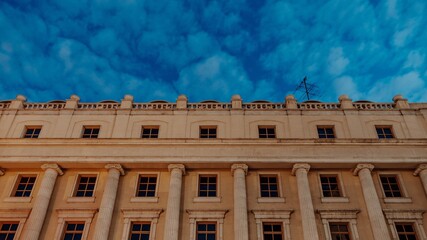 Roof of museum building on background of blue sky with clouds. Bottom shot of classic building with windows in european city with evening blue sky