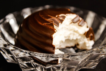 Bitten marshmallows in chocolate on a crystal bowl.