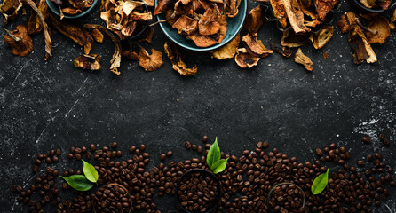 Fragrant coffee beans and dried mushrooms on a black stone background. Organic food, superfood. Top view. Free space for text.