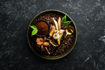 Fragrant coffee beans and dried mushrooms on a black stone background. Organic food, superfood. Top view. Free space for text.