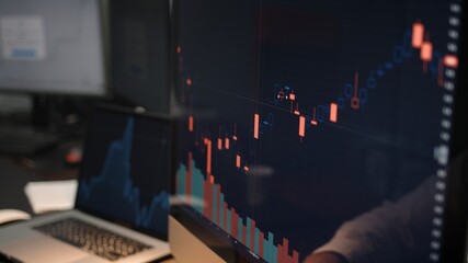 Computer screen with stock market changes, scrolling and analysing numbers. Man and computer display, no face, stock market with green and red market changes