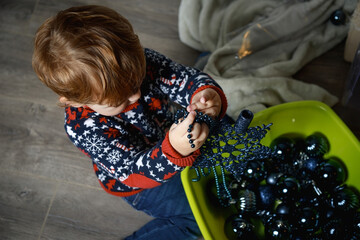 Cute little baby decorating Christmas tree. Preparing for the new year.