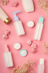 Packaging of cream, lotion, gel, facial foam or skin care. Soap and cream bottles with small flowers on pink background. Cosmetic beauty product branding mockup
