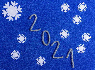 2021 and snowflakes on a blue shiny background. Christmas, winter, new year  composition. Top view.