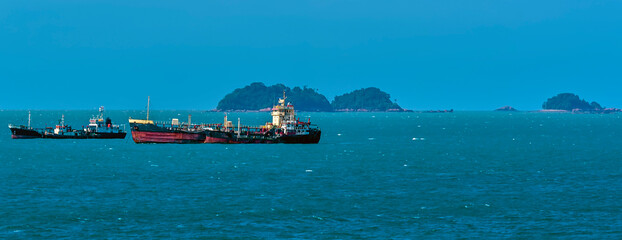 Fototapeta na wymiar A view of small tankers moored near islets in the Singapore Straits in Asia in summertime