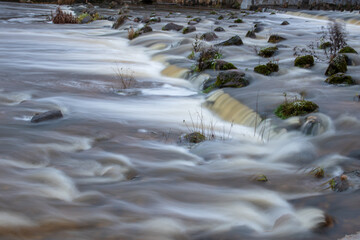 Flowing water through metal bars and stones in the river.