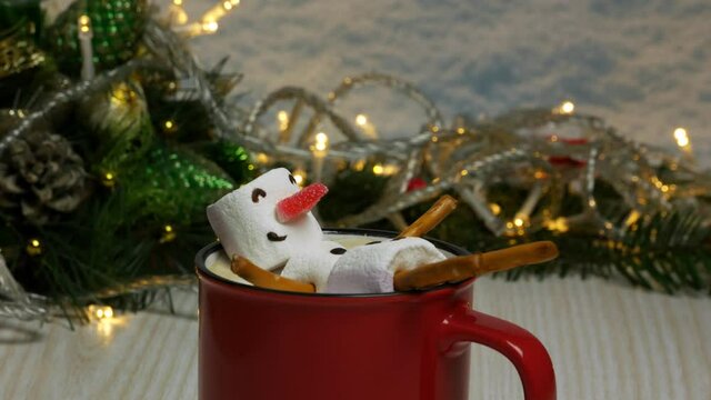 Cup of cappuccino with marshmallow snowman on christmas background 
