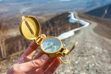 Beautiful golden compass in a man's hand against the background of mountains, travel, orientation