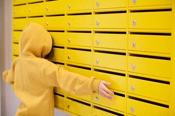 Kid peeking in yellow mailboxes