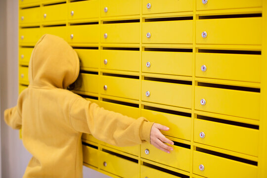 Kid Peeking In Yellow Mailboxes