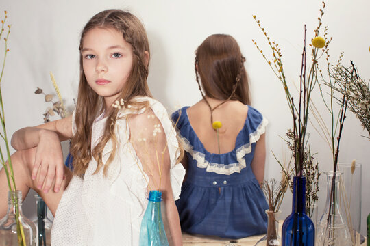 Girls in dresses among flowers on table