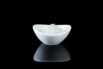 White crockery with sauce on a black background with reflection.