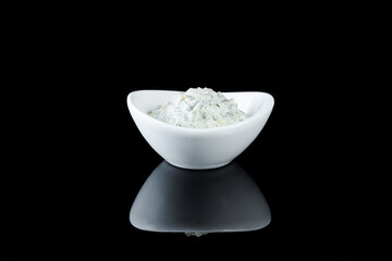 White crockery with sauce on a black background with reflection.