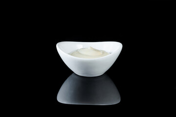White crockery with sauce on a black background with reflection.