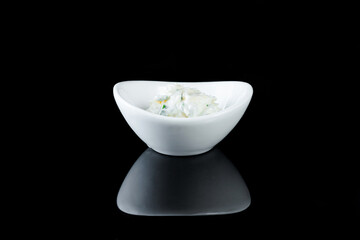 White crockery with sauce on a black background with reflection.