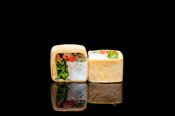 square shaped sushi wrapped in pita bread. on black background