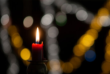 Burning candle on black background with bokeh. Christian christmas concept..