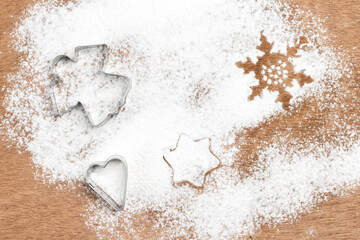 Cookie cutter molds on wooden background sprinkled with flour.